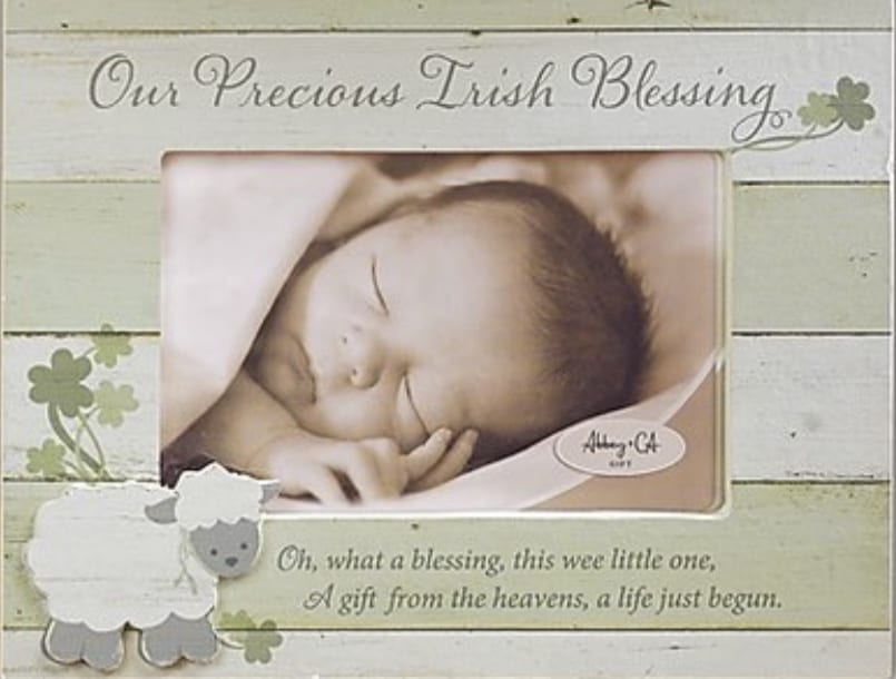A baby is laying down in front of a picture frame.