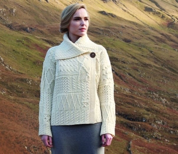 A woman in white sweater standing on top of hill.