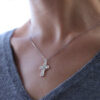 A woman wearing a cross necklace with a diamond cross.