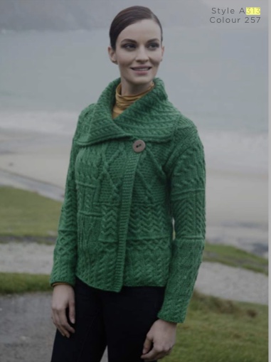 A woman standing on top of a hill wearing a green sweater.