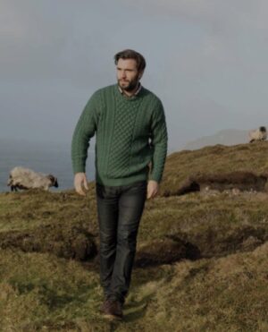 A man in green sweater walking on top of hill.