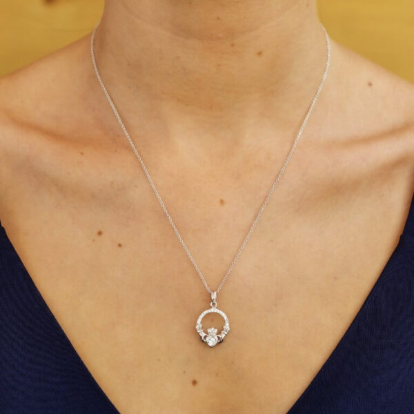 A woman wearing a necklace with a diamond in it.