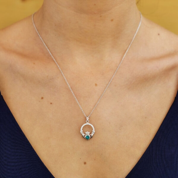 A woman wearing a necklace with a blue stone.