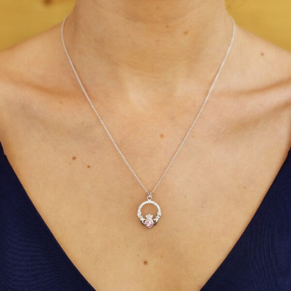 A woman wearing a necklace with a diamond in it.