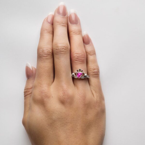 A woman 's hand with a pink ring on it
