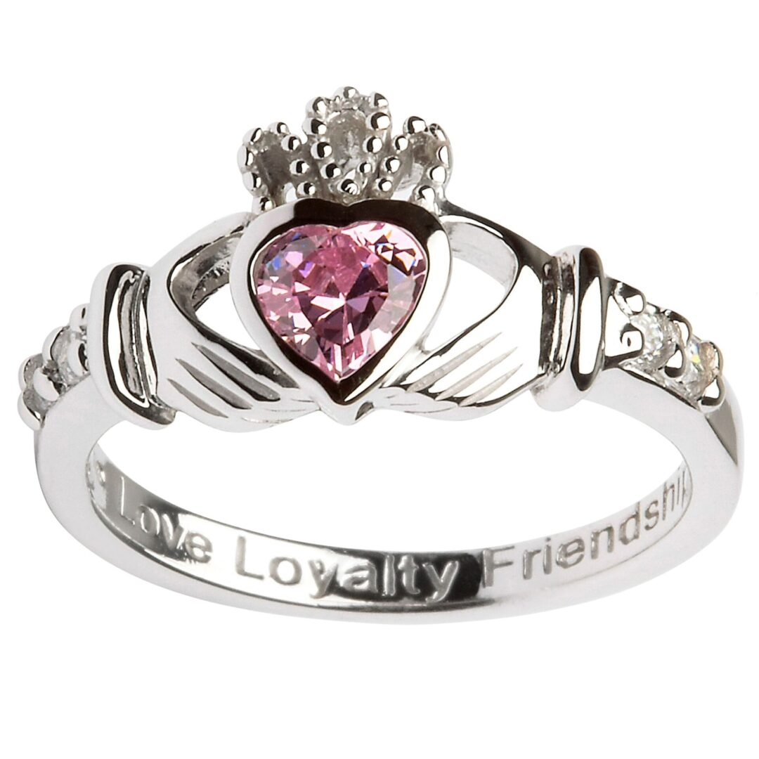 A claddagh ring with pink stone on it.