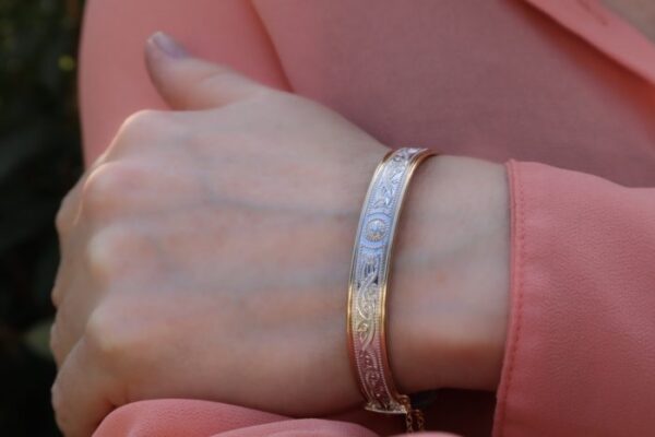 A woman 's hand wearing a bracelet with a design on it.