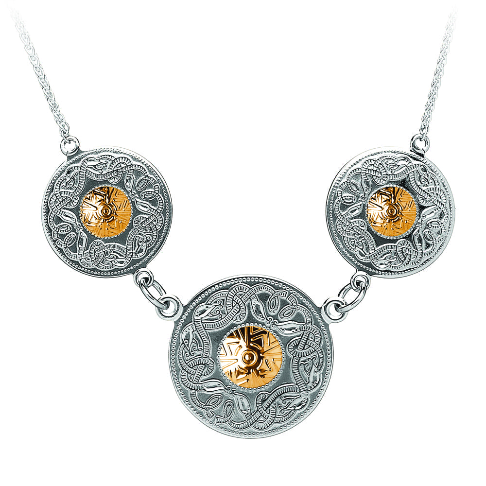 A silver necklace with three gold discs on it.