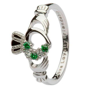 A claddagh ring with green stones on it.