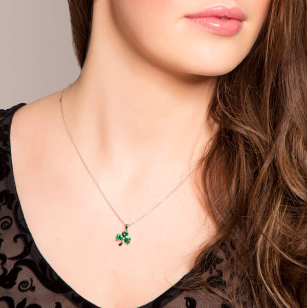 A woman wearing a necklace with four leaf clover.