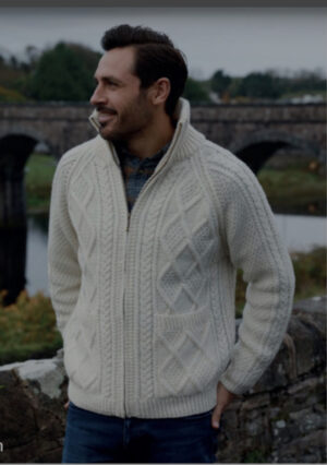 A man in a white sweater standing next to a bridge.