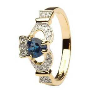 A gold ring with a blue stone and diamond claddagh.