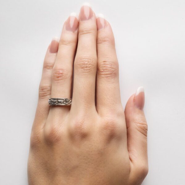 A woman 's hand with a wedding ring on it.