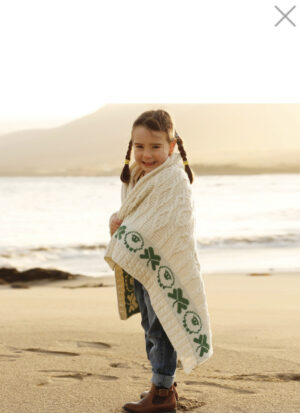 A little girl wrapped in a blanket on the beach