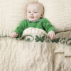 A baby is laying in bed with a blanket.