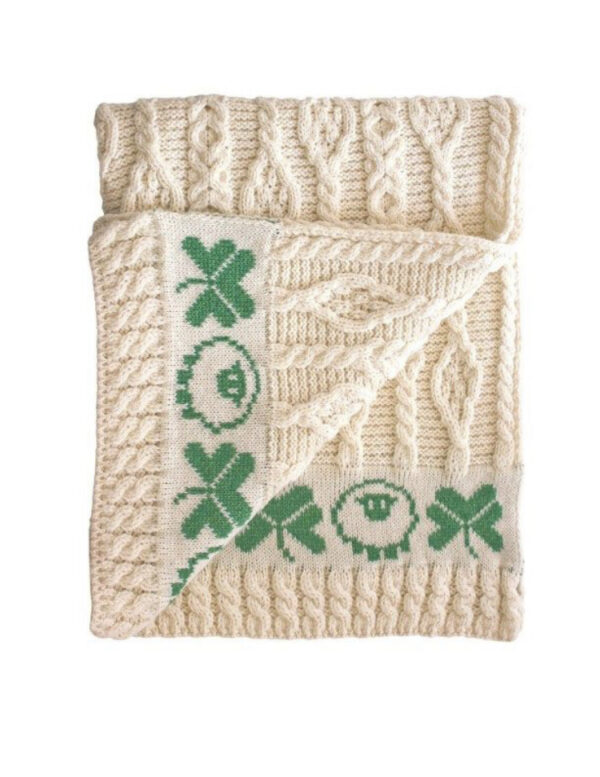 A white blanket with green designs on it.