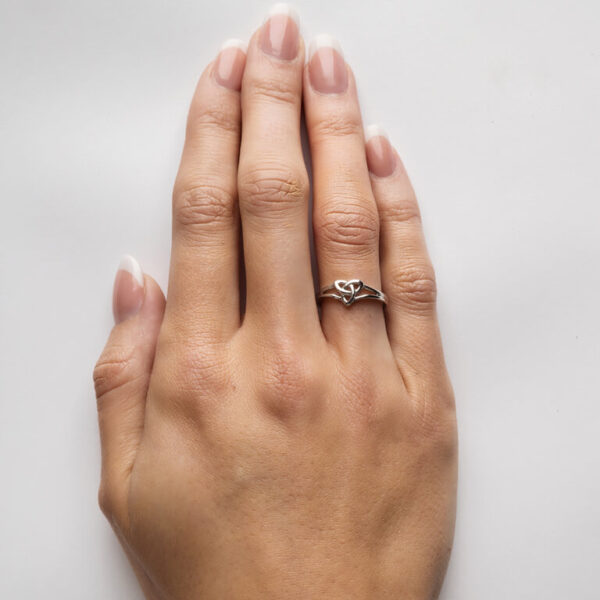 A woman 's hand with a wedding ring on it.