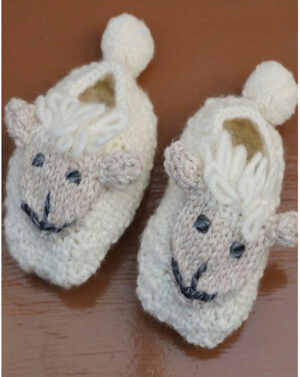 A pair of knitted sheep slippers on top of a wooden table.