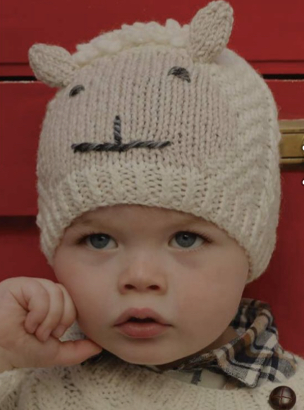 A baby wearing a hat with an animal face on it.