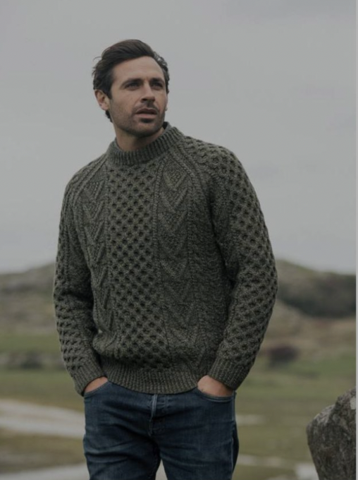 A man in a sweater standing on top of a hill.