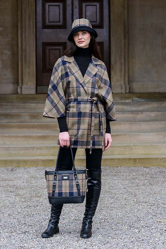 A woman in plaid coat and black boots holding a purse.