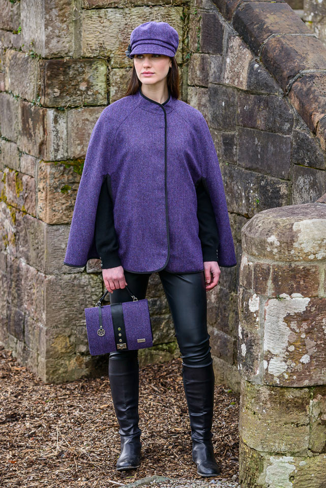 A woman in purple jacket holding a purse.