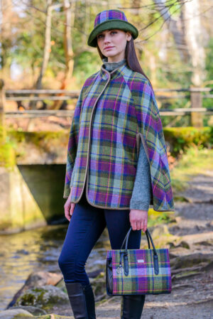 A woman in plaid cape holding a purse.