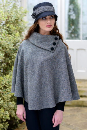 A woman wearing a gray poncho with buttons on the side.