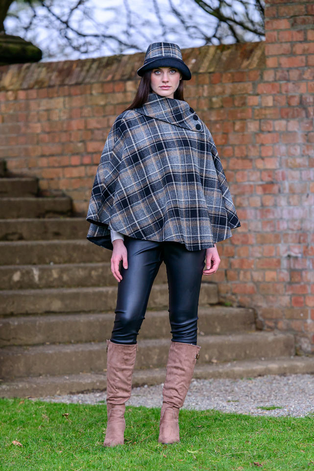 A woman in boots and a plaid poncho.