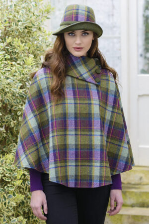 A woman wearing a plaid poncho standing outside.