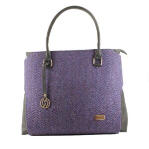 A purple bag with a leather handle and a metal tag.