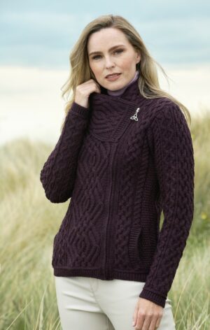 A woman in a purple sweater standing on top of a beach.