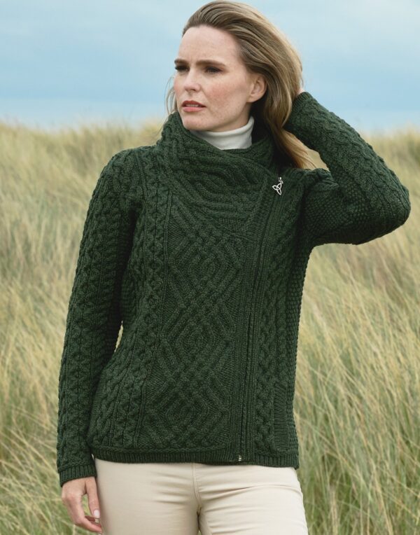 A woman in green sweater standing on top of grass.