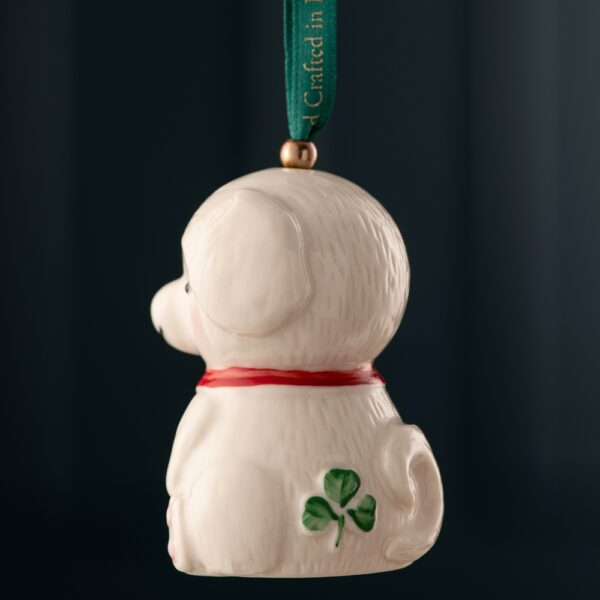 A white dog ornament hanging from a green ribbon.