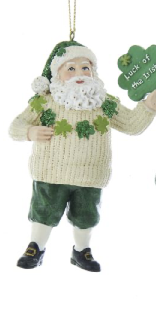 A man in green shorts and sweater holding a shamrock.