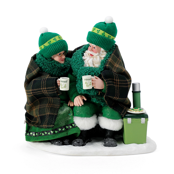 Two people dressed as leprechauns sitting on a blanket.