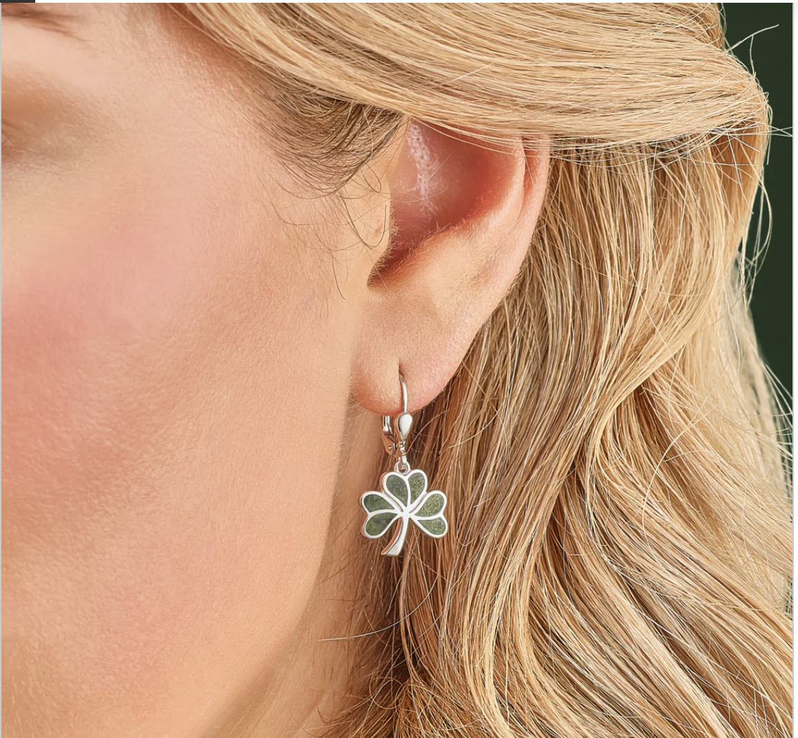 Close-up of a woman's ear wearing a delicate flower-shaped earring.
