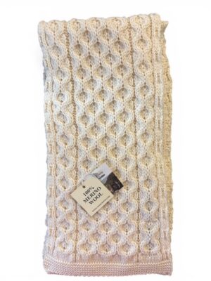 Cream cable knit wool blanket with label.