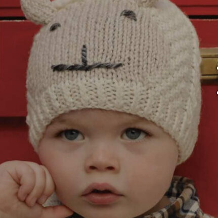 A baby wearing a hat with an animal face on it.
