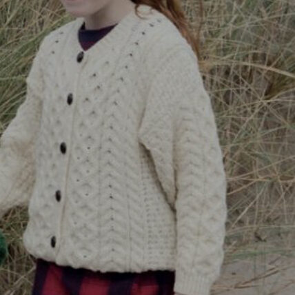 A girl in a white sweater standing outside.