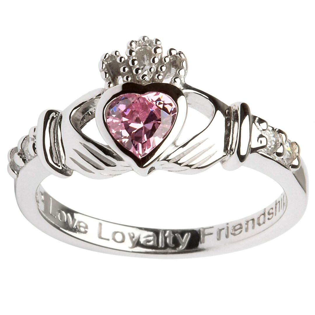 A claddagh ring with pink stone on it.