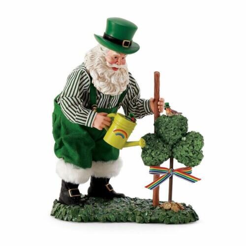 A man in green and white outfit watering a tree.