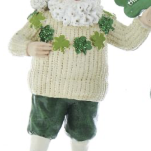A man in green shorts and sweater holding a shamrock.