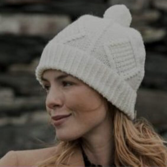 A woman wearing a white hat with a pom-pom.