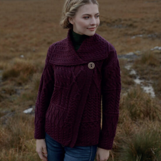 A woman in purple sweater standing on top of a hill.