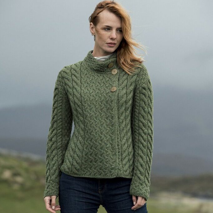 A woman in green sweater standing on top of hill.