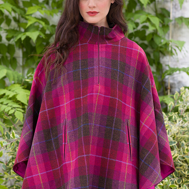 A woman in a plaid poncho standing outside.