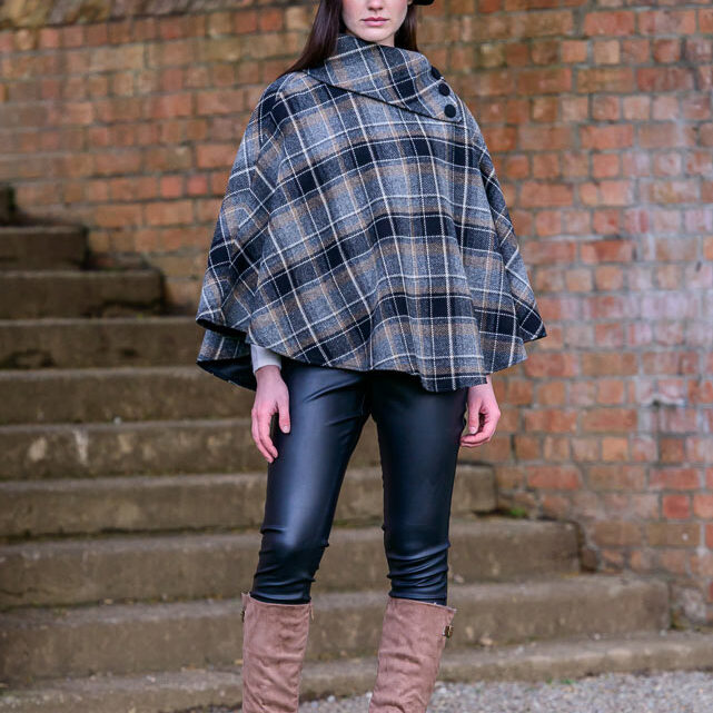 A woman in boots and a plaid poncho.