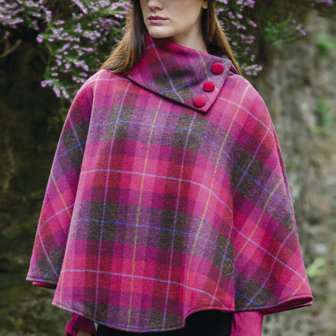 A woman in a pink plaid poncho with buttons.
