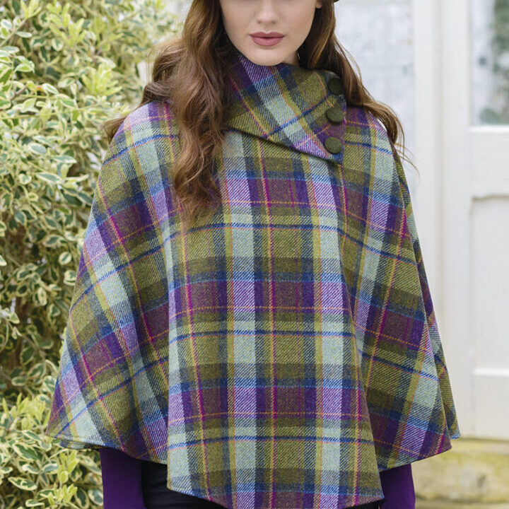 A woman wearing a plaid poncho standing outside.